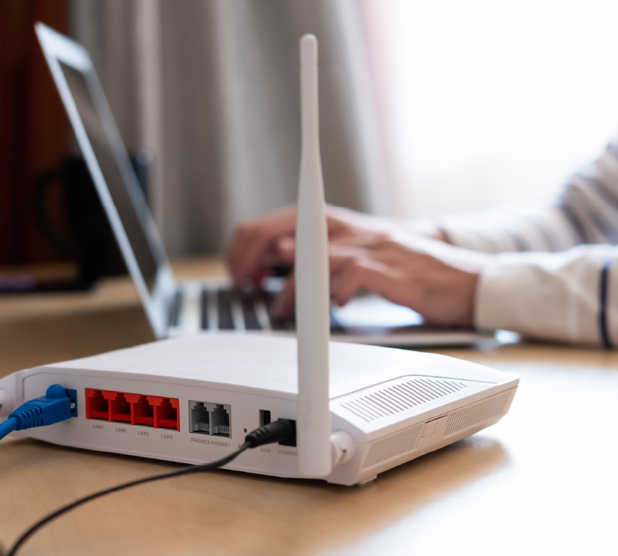 Photo of modem with computer user in background.