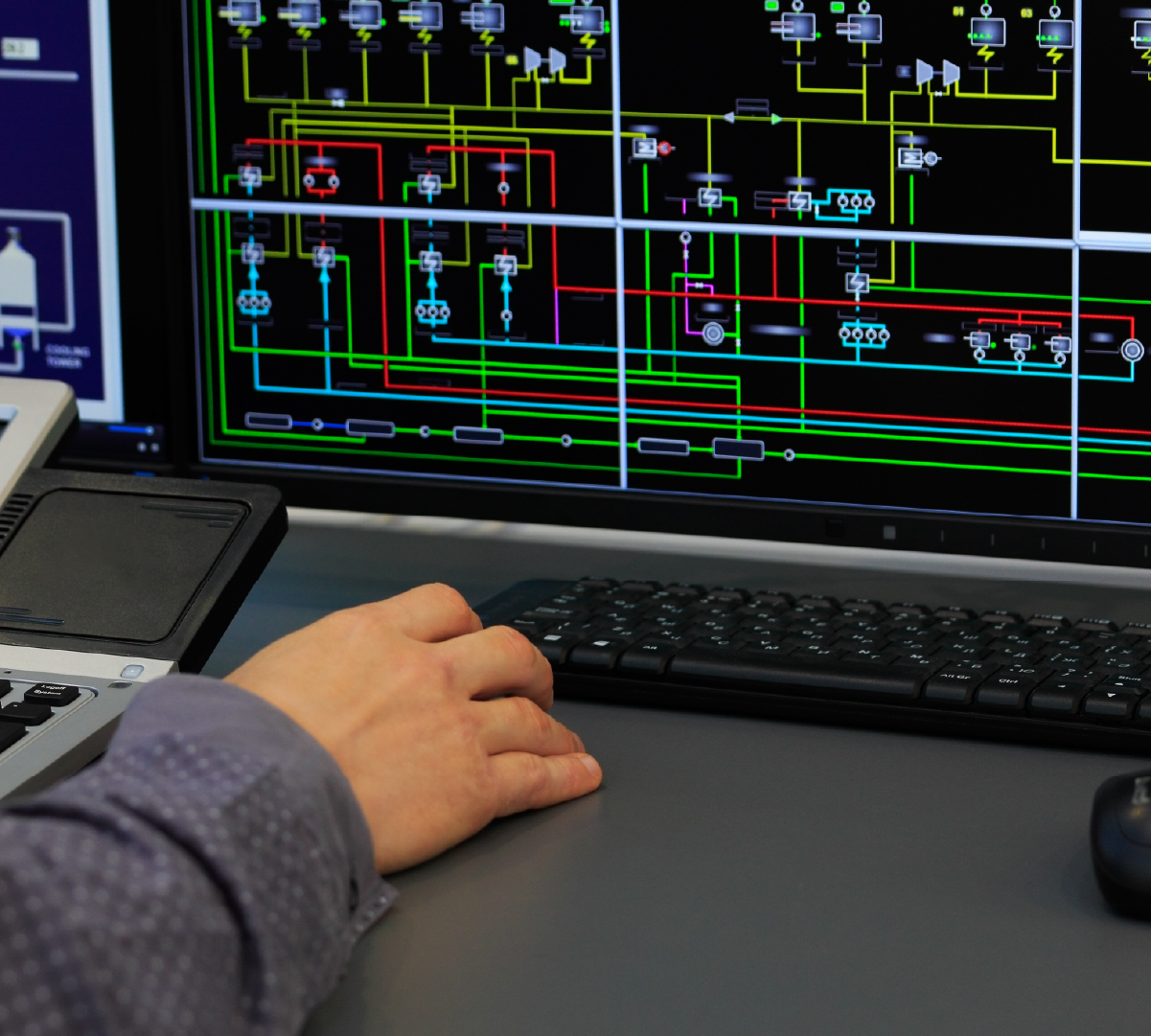 User at computer with SCADA industrial controls shown on screen